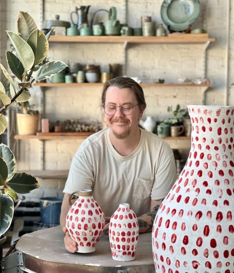 Lucas Mays in his studio with red dotted pottery