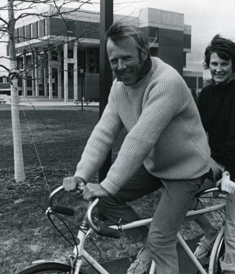 Chuck and Polly Longsworth riding a bike on the Hampshire campus
