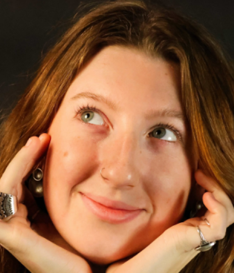 Mia Sullivan F22 smiling with her hands cupping her face.