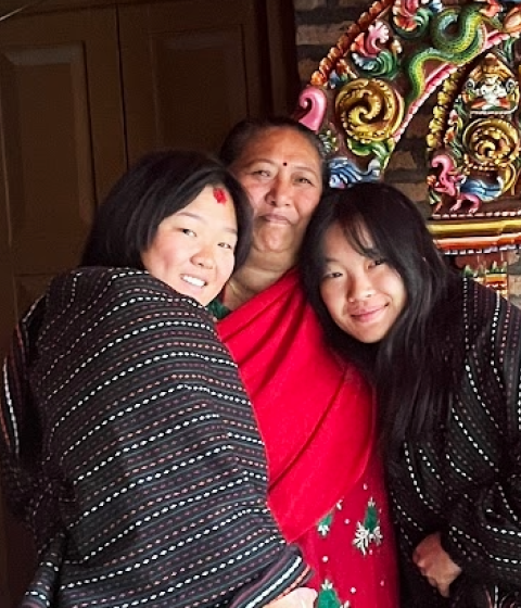 Three people smiling with arms around each other in front of a colorful sculpture.