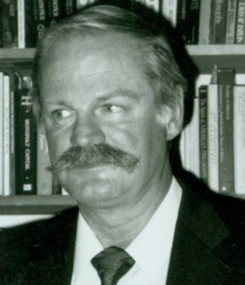 Stanley Warner in black and white in front of shelves full of books