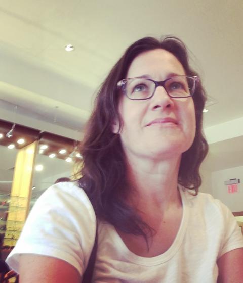 A person in glasses and a white t-shirt looking up.