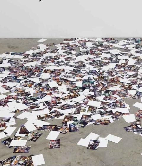 Photos scattered on a concrete floor, an installation by Anthony Discenza