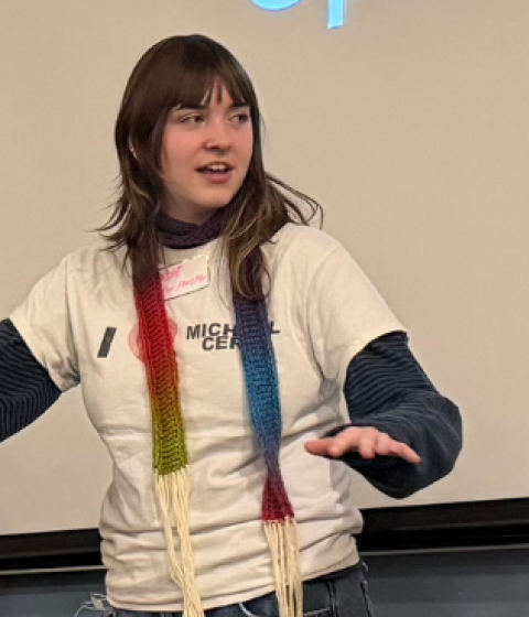 Three people standing in front of a whiteboard talking; one is holding a board game.